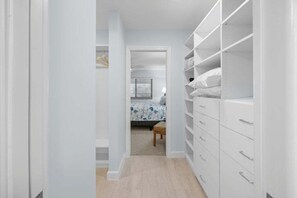 Ein schmaler Flur, der zu einem Schlafzimmer mit Bett und Nachttisch führt.