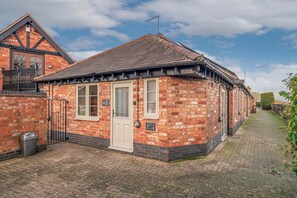 A brick building with a tiled roof, a door, and a window.
