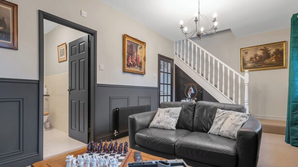 A living room with a chessboard, a leather sofa, and a staircase.
