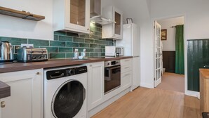 A compact kitchen with a washing machine, a toaster, and a microwave.