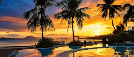 A pool with palm trees and a sunset view.
