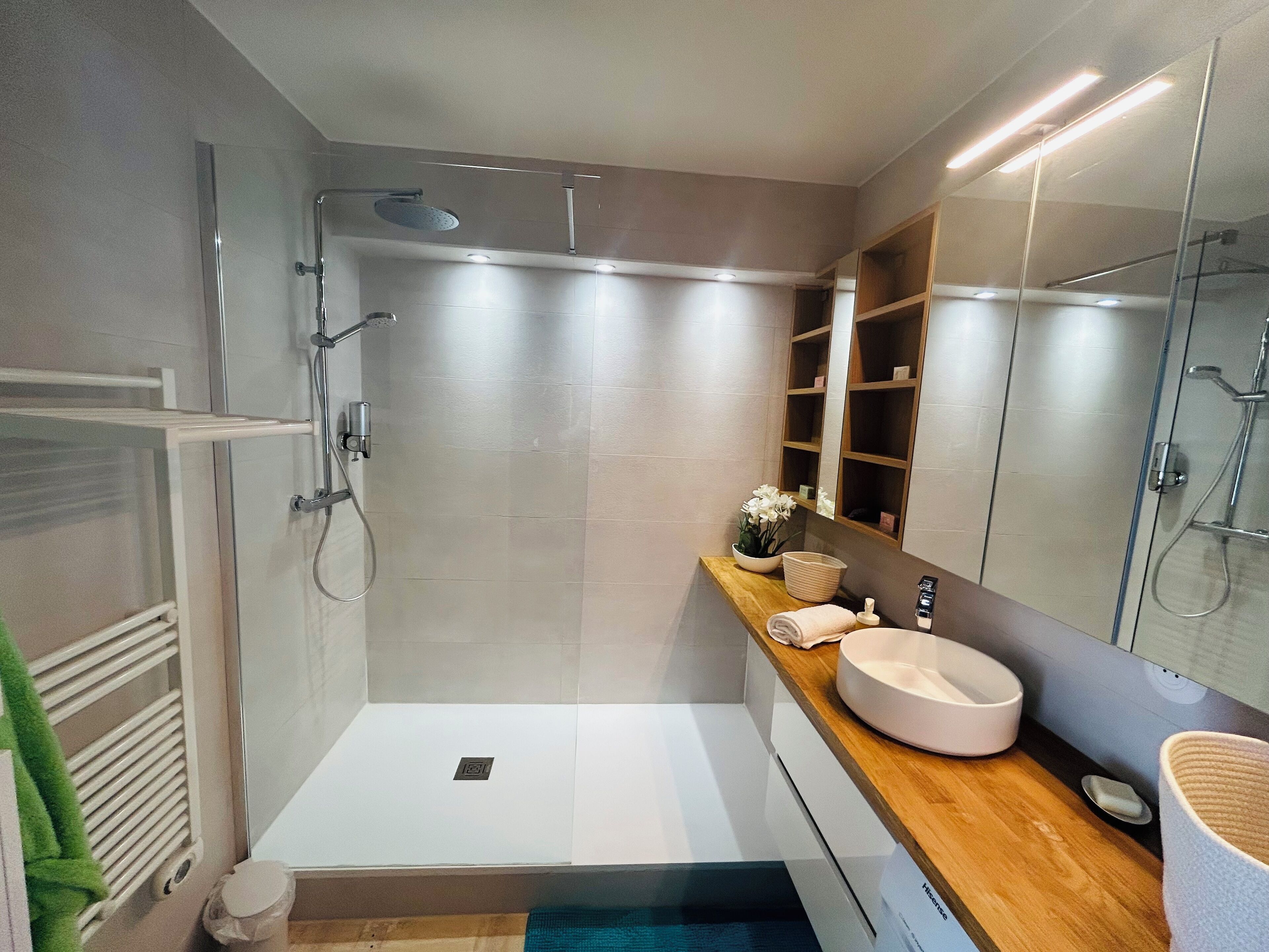 A modern bathroom with a walk-in shower, a vanity with a sink, and a large mirror.