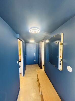 Ein Flur mit blauen Wänden, Holzdielen und einem Spiegel an einer Wand.