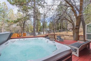 Ein Whirlpool auf einer Terrasse mit Sitzgelegenheiten im Freien und Bäumen im Hintergrund.
