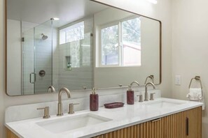 Ein Badezimmer mit einem großen Spiegel, zwei Waschbecken und einer Dusche.