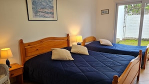Habitación con dos camas, cada una con cabecero de madera, una mesita de noche con lámpara y un cuadro enmarcado en la pared.