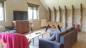 A living room with a sofa, a TV, a wooden table, and a foosball table.