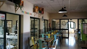 A dining area with colorful chairs and tables, a glass door entrance, and a ceiling with recessed lighting. - Bungalow with Terrace - Sleeps 2 (Humilladero)