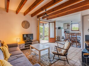 A cozy living room with a sofa, TV, and a dining area with chairs and a table. - Semi-detached house in Sanguinet, near lake, with garden and Wi-Fi (Sanguinet)