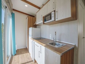 A compact kitchen with a microwave, sink, and wooden cabinets. - Charming Bungalow for 2 with Terrace (crevillente)