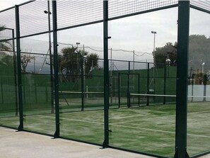 Ein Tennisplatz, umzäunt mit einem grünen Zaun und einem Netz.