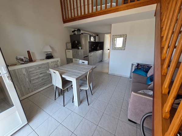 A compact living space with a dining table, kitchenette, and a sofa.