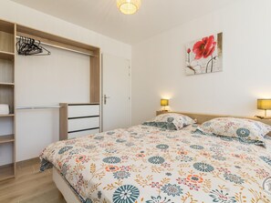 Ett sovrum med en säng, sänglampor, en garderob och en blomstermålning på väggen.