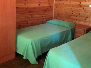 A small, single-room cabin with two beds, a wooden wall, and a wooden nightstand. - Bungalow with Terrace in Marbella - Perfect for Couples (Marbella)