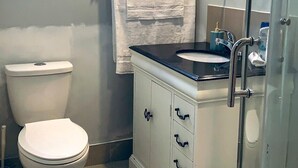 A bathroom with a toilet, a sink with a mirror, and a shower area. - yonge & finch subway cozy rooms for rent (Toronto)