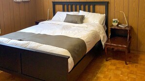 A wooden-paneled bedroom with a bed, a nightstand with a lamp, and a framed picture on the wall. - yonge & finch subway cozy rooms for rent (Toronto)