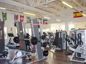 A gym with various exercise equipment, flags on the walls, and a high ceiling. - Bungalow with Terrace - 2 Guests (Crevillente)