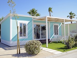 A modern, single-story building with a light blue exterior, large windows, and a covered outdoor seating area. - Bungalow with Terrace - 2 Guests (Crevillente)
