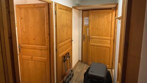 Un passadís amb portes de fusta, una maleta i un carret petit.