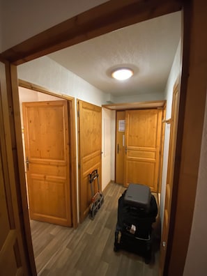 A hallway with wooden doors, a suitcase, and a small cart. - A Mont Blanc summer biking and hiking hub and winter skiing on your doorstep. (Saint-Gervais-les-Bains)