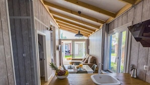 A compact kitchen with wooden cabinets, a sink, and a dining area with a table and chairs. - Bungalow with Terrace and Accessible Ramp in Guardamar (Guardamar del Segura)