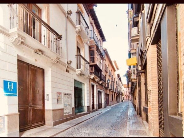 A narrow street lined with multi-story buildings, featuring balconies and a mix of architectural styles. - Charming 18th-century home in Granada, parking included (Granada)