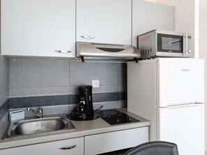 A compact kitchen with a sink, a coffee maker, a microwave, and a refrigerator. - Air-Conditioned Studio with Parking Near the Beach (Narbonne-Narbonne Plage-Narbonne Plage)