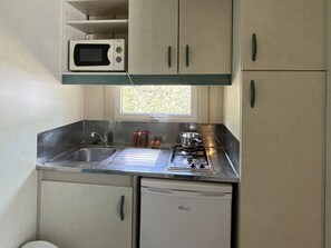 Una kitchenette compacta equipada con microondas, fregadero, cocina y lavavajillas pequeño.