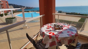 A balcony with a table set for two, overlooking a swimming pool and the sea. - 2-room apartment, 4 people, sea view, pool & parking (Sète)