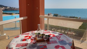 A balcony with a table set for two, overlooking a pool and the sea. - 2-room apartment, 4 people, sea view, pool & parking (Sète)
