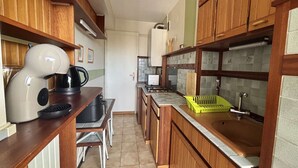 Une cuisine compacte avec des meubles en bois, une machine à café, un évier et un petit coin repas.