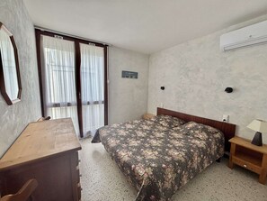 A bedroom with a bed, a desk, a chair, a nightstand, and a window with curtains. - Air-Conditioned T2 Apartment for 4 in Argelès-sur-Mer with Parking (Argelès-sur-Mer)