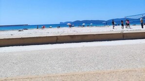 A beach with people, umbrellas, and a volleyball net. - Apartment Le Pavoncelle Lido ideal for Families (Alghero)