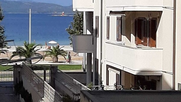 A multi-story building with balconies overlooking a beach and the sea. - Apartment Le Pavoncelle Lido ideal for Families (Alghero)