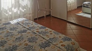 A bedroom with a bed, a chair, a wardrobe, and a mirror. - Apartment Le Pavoncelle Lido ideal for Families (Alghero)
