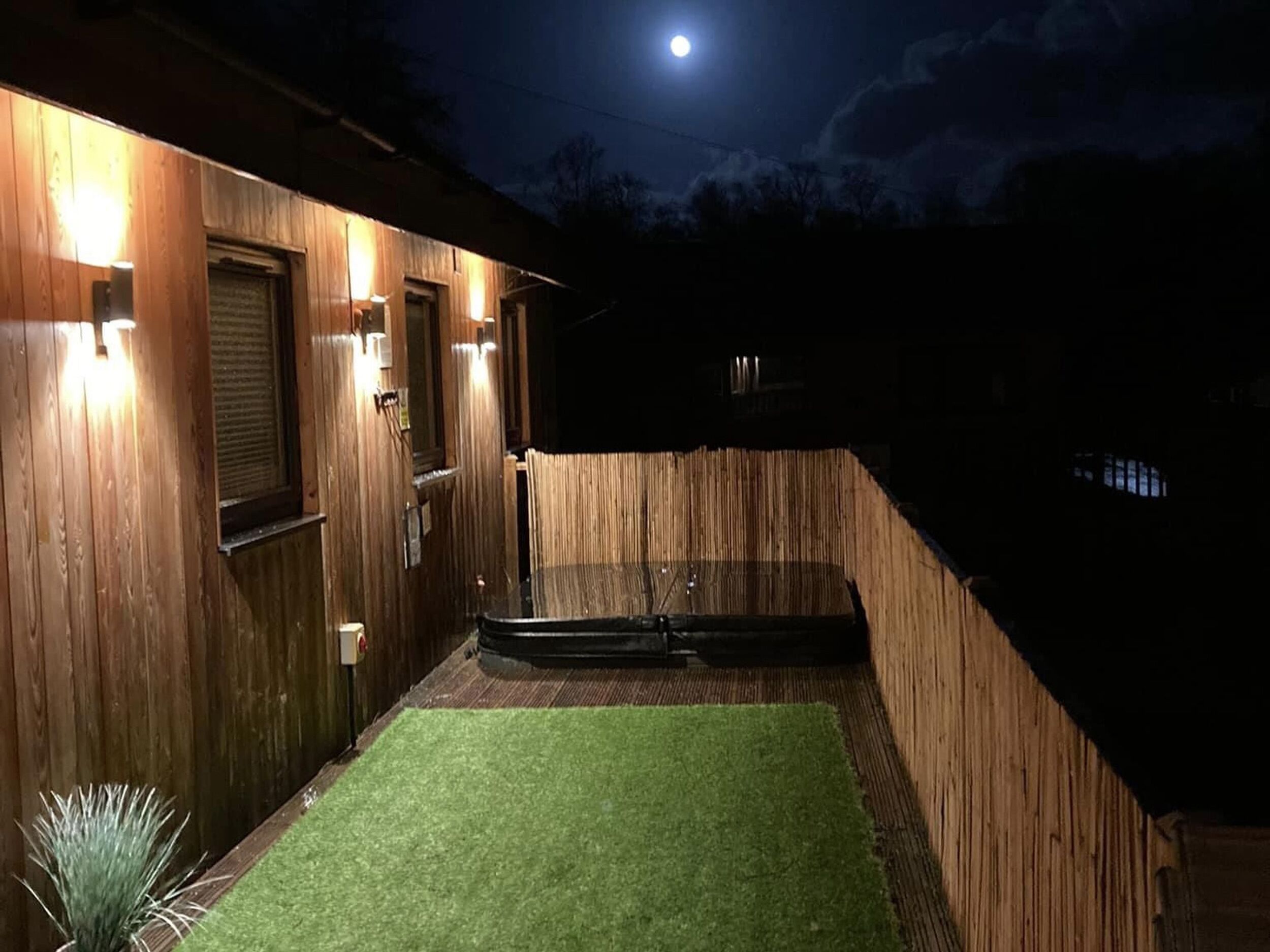 Ein Holzhaus mit einer kleinen Rasenfläche und einem Mond am Himmel.