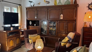 Un salon avec un téléviseur, des meubles en bois, une lampe et des objets décoratifs accrochés au mur.