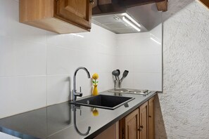 A kitchen with a black countertop, stainless steel sink, and wooden cabinets. - Holiday Home 'Le Mas' with Mountain View, Wi-Fi, Air Conditioning (Arles-sur-Tech)