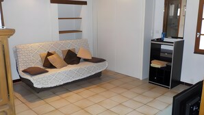 A living room with a sofa, a television, and a wooden cabinet.