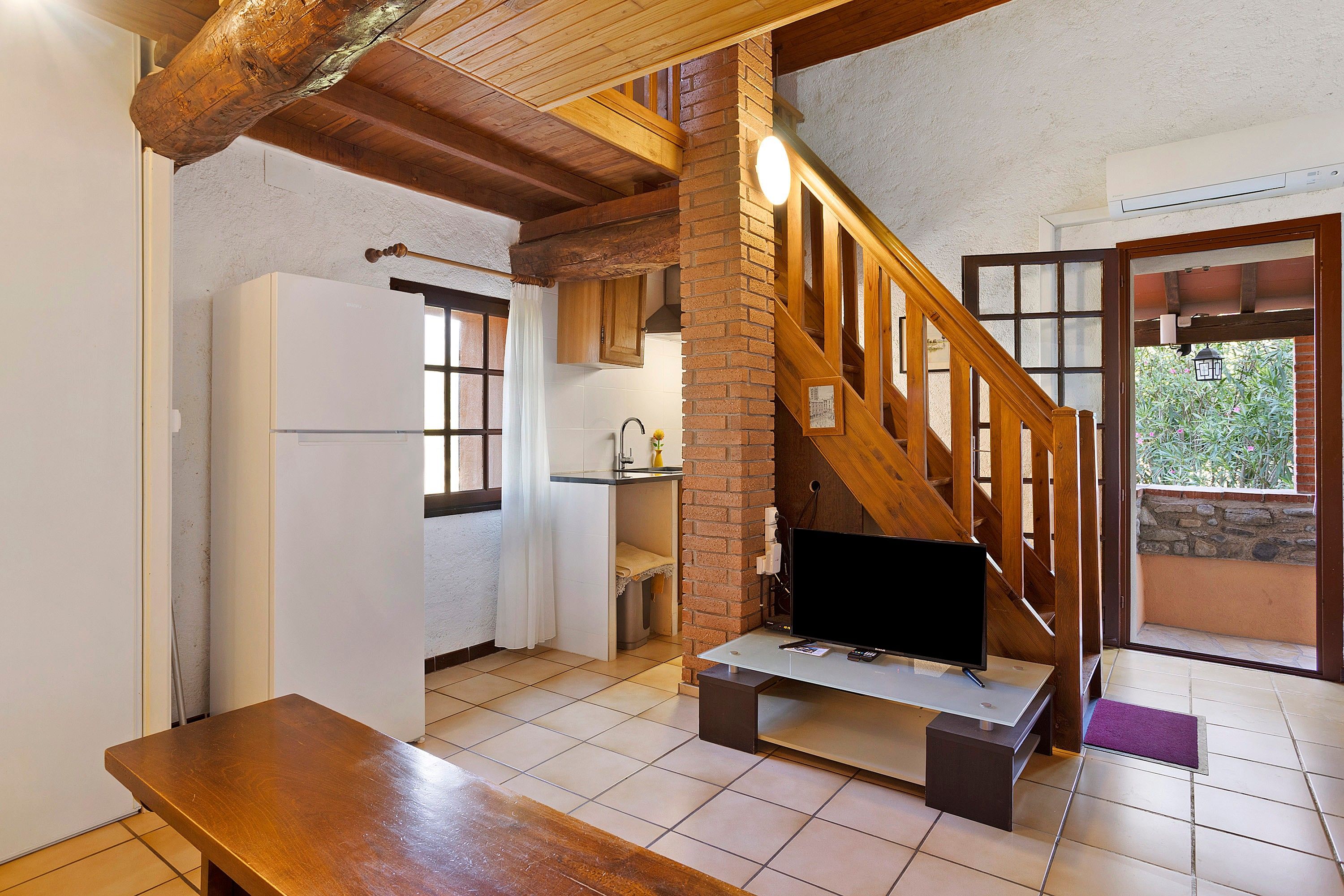 Una cocina con escaleras de madera, un refrigerador y una mesa de comedor.