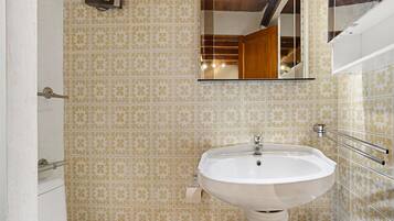 A bathroom with patterned tiles, a white sink, and a mirror.