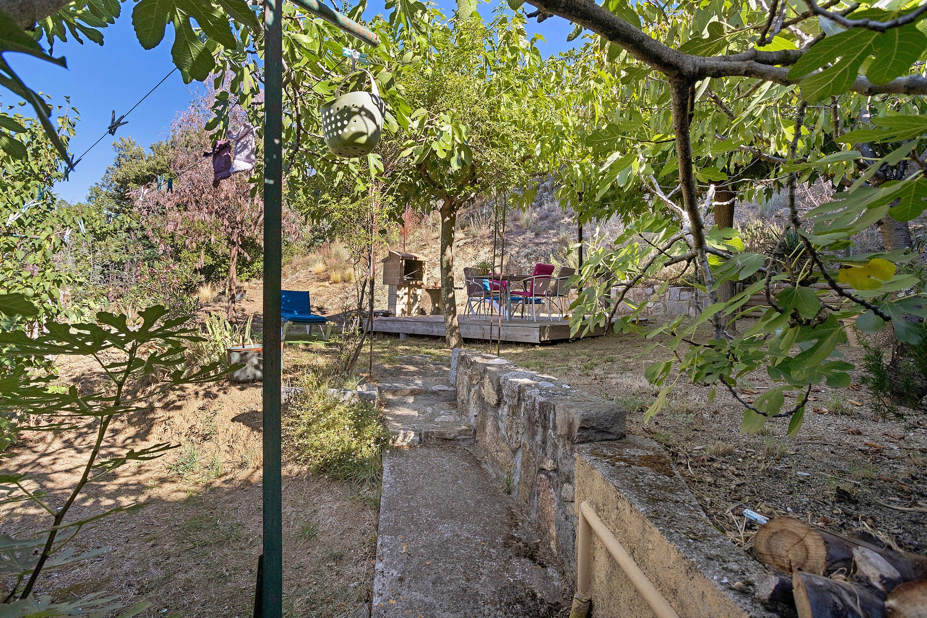 Ein Garten mit einer Steinsäule, einer Holzterrasse und einem Vogelhaus.