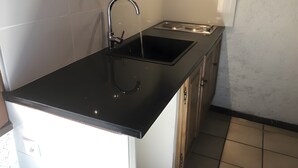 A kitchen with a black countertop, stainless steel sink, and a stove.