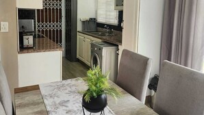 Un espacio habitable compacto con comedor, kitchenette y lavadora.