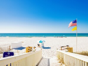 Ein Strand mit einer Holzpromenade, Liegestühlen, Sonnenschirmen und einer amerikanischen Flagge.