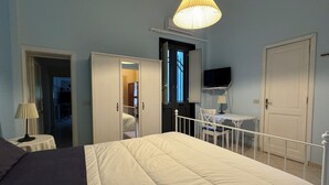 A bedroom with a bed, bedside table, lamp, wardrobe, and a television on a stand. - The House Before the Sea (Fiumefreddo Sicilia)