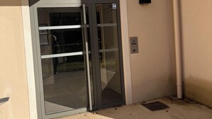 Uma entrada de prédio com porta de vidro, moldura de metal e uma pequena placa acima da porta.