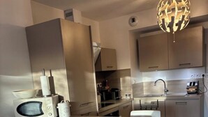 Uma cozinha moderna com ilha central, eletrodomésticos de aço inoxidável e uma luminária esférica singular.