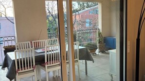 Uma porta de correr de vidro dá para um pátio externo com mesa e cadeiras.