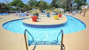 A swimming pool with a tiled edge, a pool ladder, and several potted plants around the perimeter. - Cozy 2-bedroom condo at Myrtle Beach Resort (Myrtle Beach)